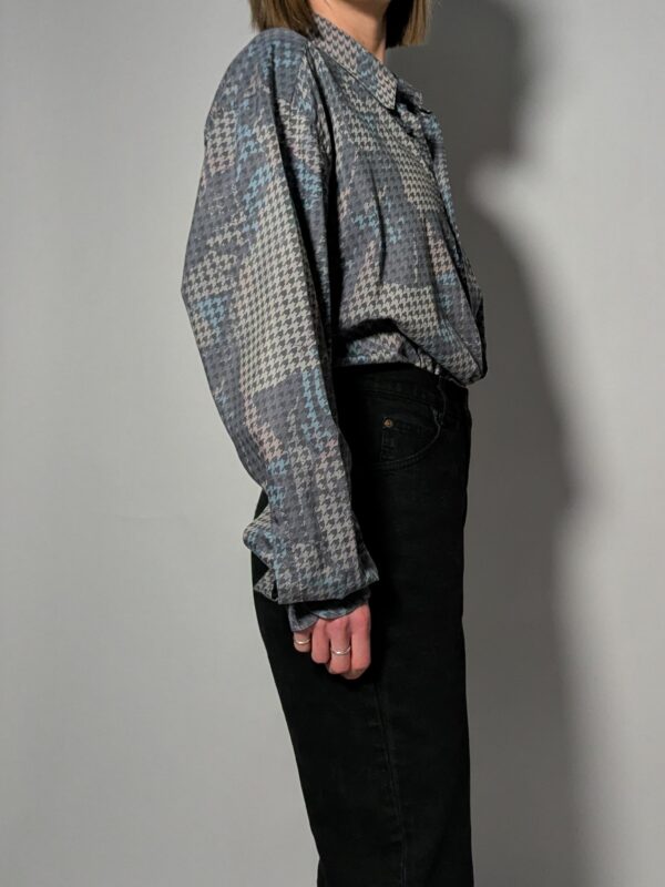 Vintage blouse met houndstooth patroon in zachte grijstinten. Licht, stijlvol en veelzijdig.