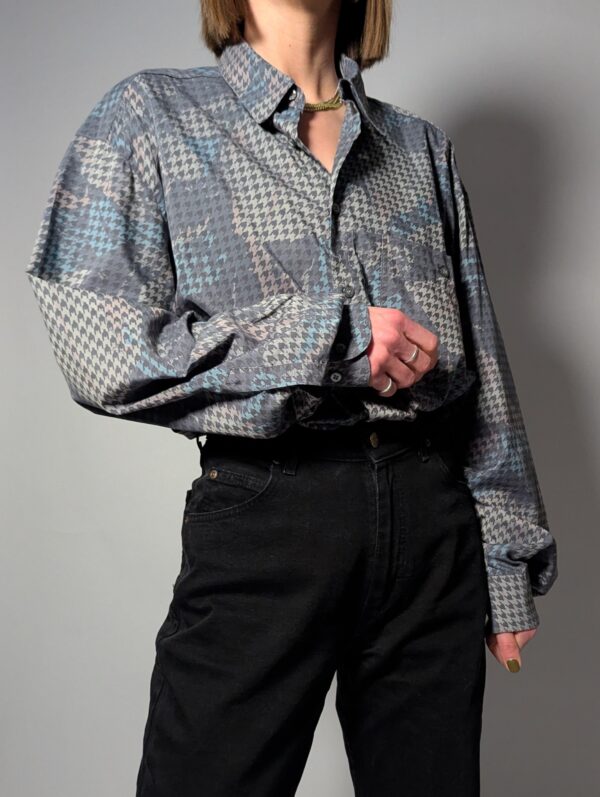 Vintage blouse met houndstooth patroon in zachte grijstinten. Licht, stijlvol en veelzijdig.