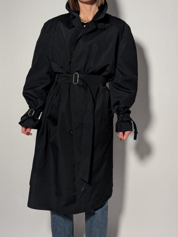 Vintage zwarte trenchcoat met ceintuur. Tijdloos silhouet en elegante uitstraling.