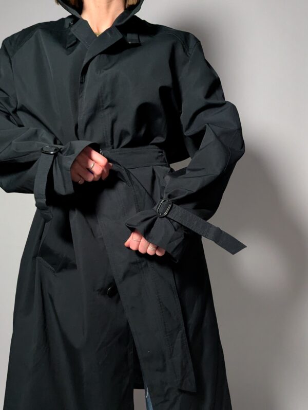 Vintage zwarte trenchcoat met ceintuur. Tijdloos silhouet en elegante uitstraling.