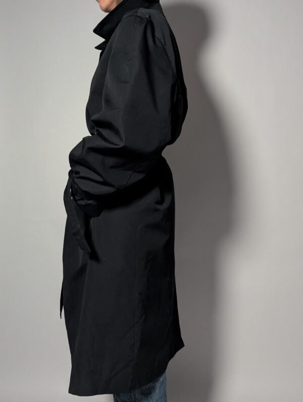 Vintage zwarte trenchcoat met ceintuur. Tijdloos silhouet en elegante uitstraling.