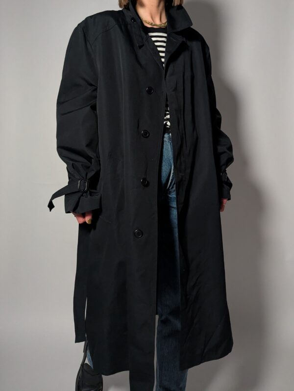 Vintage zwarte trenchcoat met ceintuur. Tijdloos silhouet en elegante uitstraling.