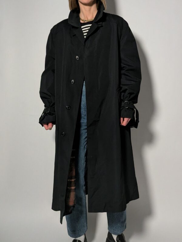 Vintage zwarte trenchcoat met ceintuur. Tijdloos silhouet en elegante uitstraling.