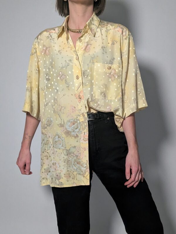 Pastelgele vintage blouse met korte mouwen, oversized fit, bloemenprint en subtiele stipdetails.