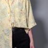 Pastelgele vintage blouse met korte mouwen, oversized fit, bloemenprint en subtiele stipdetails.