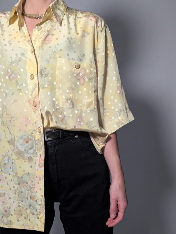 Pastelgele vintage blouse met korte mouwen, oversized fit, bloemenprint en subtiele stipdetails.