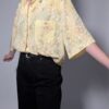 Pastelgele vintage blouse met korte mouwen, oversized fit, bloemenprint en subtiele stipdetails.