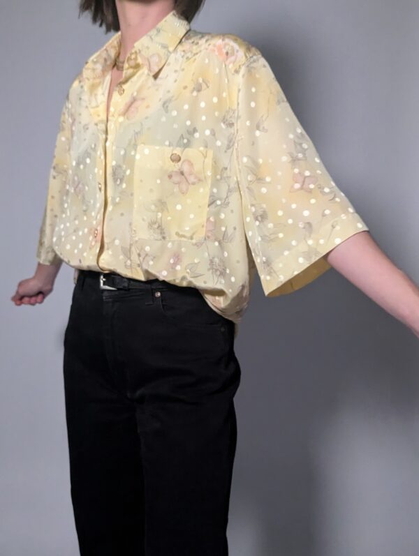 Pastelgele vintage blouse met korte mouwen, oversized fit, bloemenprint en subtiele stipdetails.