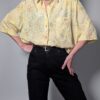 Pastelgele vintage blouse met korte mouwen, oversized fit, bloemenprint en subtiele stipdetails.