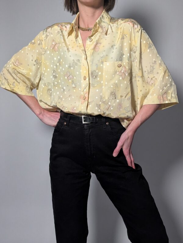 Pastelgele vintage blouse met korte mouwen, oversized fit, bloemenprint en subtiele stipdetails.