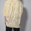 Pastelgele vintage blouse met korte mouwen, oversized fit, bloemenprint en subtiele stipdetails.