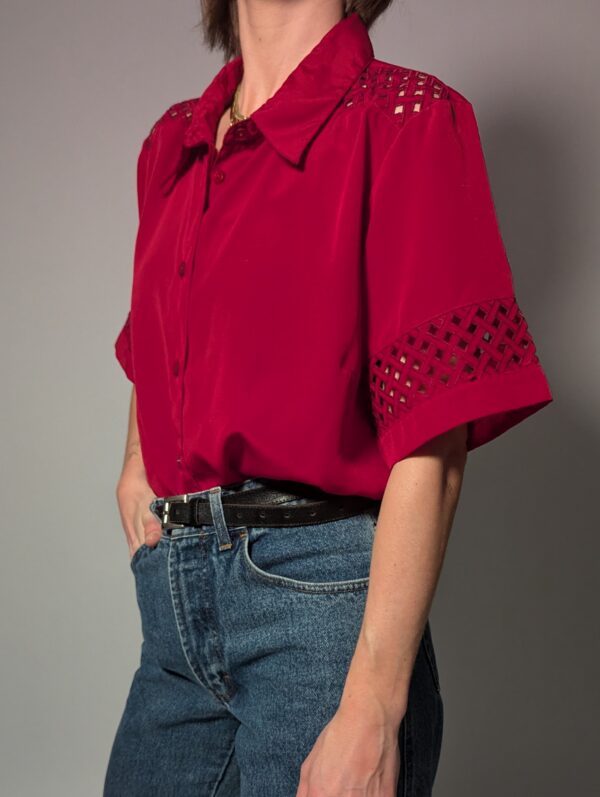 Kersenrode vintage blouse met korte mouwen, glanzende stof en opengewerkte details op schouders en mouwen.