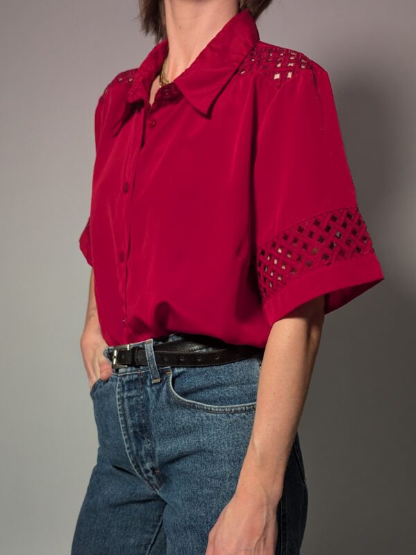 Kersenrode vintage blouse met korte mouwen, glanzende stof en opengewerkte details op schouders en mouwen.