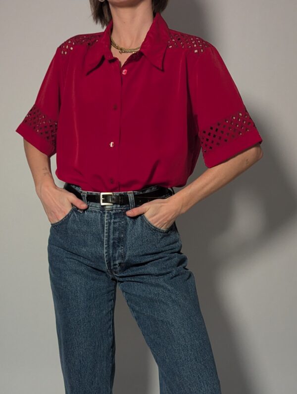 Kersenrode vintage blouse met korte mouwen, glanzende stof en opengewerkte details op schouders en mouwen.