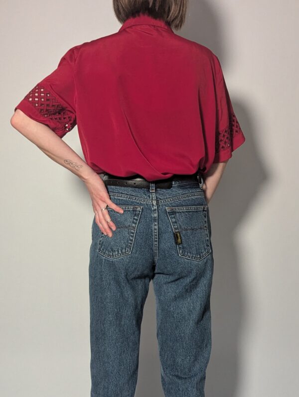 Kersenrode vintage blouse met korte mouwen, glanzende stof en opengewerkte details op schouders en mouwen.