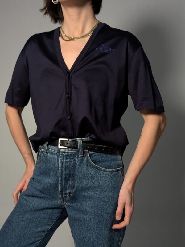 Donkerblauwe vintage topmet korte mouwen, diepe V-hals, subtiele glans en fijne knoopdetails.