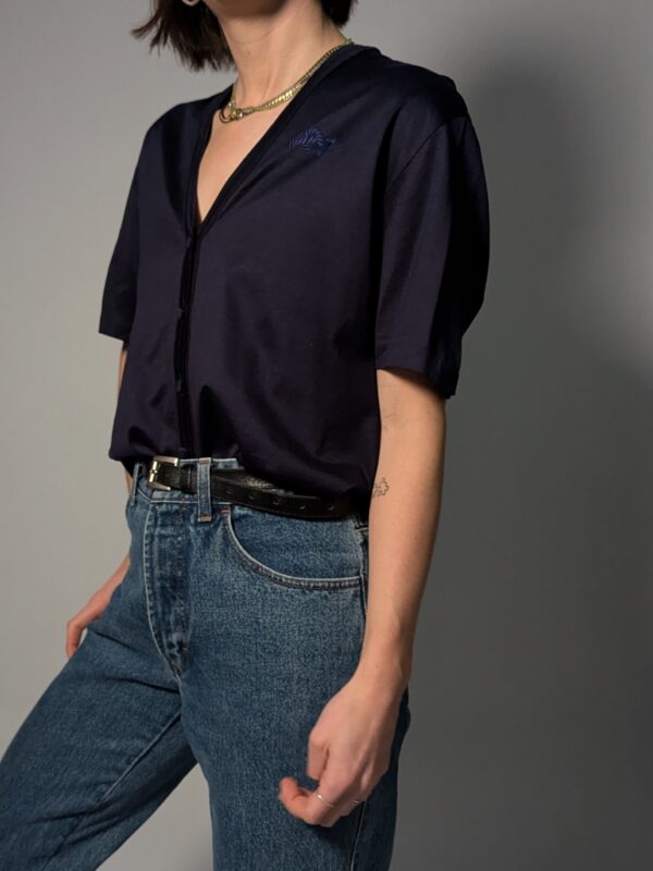 Donkerblauwe vintage topmet korte mouwen, diepe V-hals, subtiele glans en fijne knoopdetails.
