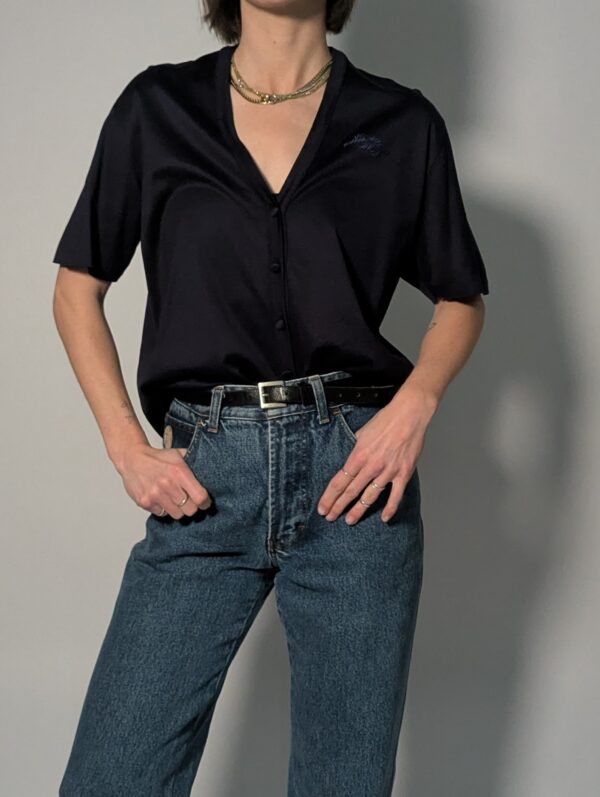 Donkerblauwe vintage topmet korte mouwen, diepe V-hals, subtiele glans en fijne knoopdetails.