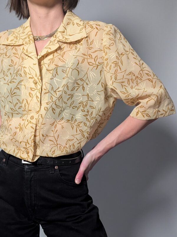 Lichtbeige vintage blouse met korte mouwen, botanische print in honingtinten en elegante kraag.
