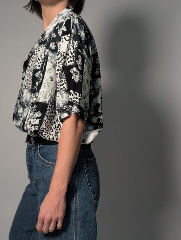 Zwart-witte vintage blouse met korte mouwen en gemixte patchwork print van bloemen- en animal motieven.