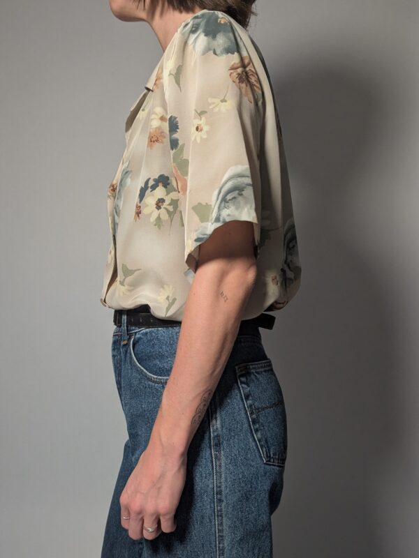 Vintage blouse met korte mouwen in zachte zandtint met bloemenprint in blauw, crème en warme nudetinten.