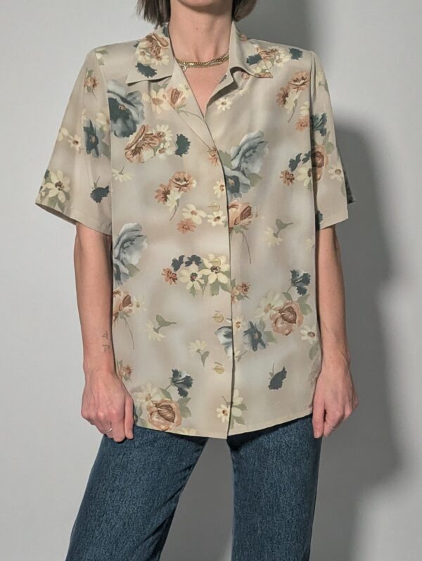 Vintage blouse met korte mouwen in zachte zandtint met bloemenprint in blauw, crème en warme nudetinten.