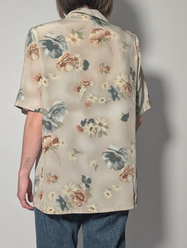 Vintage blouse met korte mouwen in zachte zandtint met bloemenprint in blauw, crème en warme nudetinten.