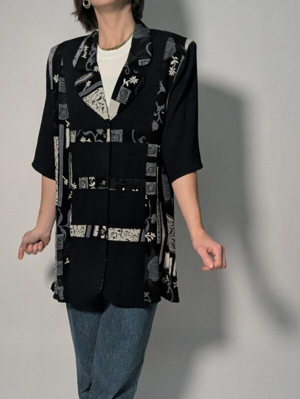 Zwarte vintage lange blouse met korte mouwen en grafisch patchworkpatroon in zwart-wit en grijstinten.