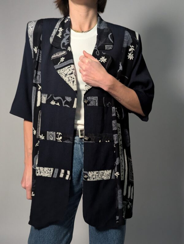 Zwarte vintage lange blouse met korte mouwen en grafisch patchworkpatroon in zwart-wit en grijstinten.