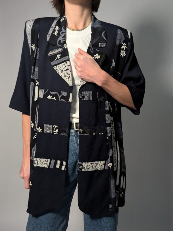 Zwarte vintage lange blouse met korte mouwen en grafisch patchworkpatroon in zwart-wit en grijstinten.