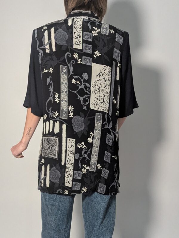 Zwarte vintage lange blouse met korte mouwen en grafisch patchworkpatroon in zwart-wit en grijstinten.