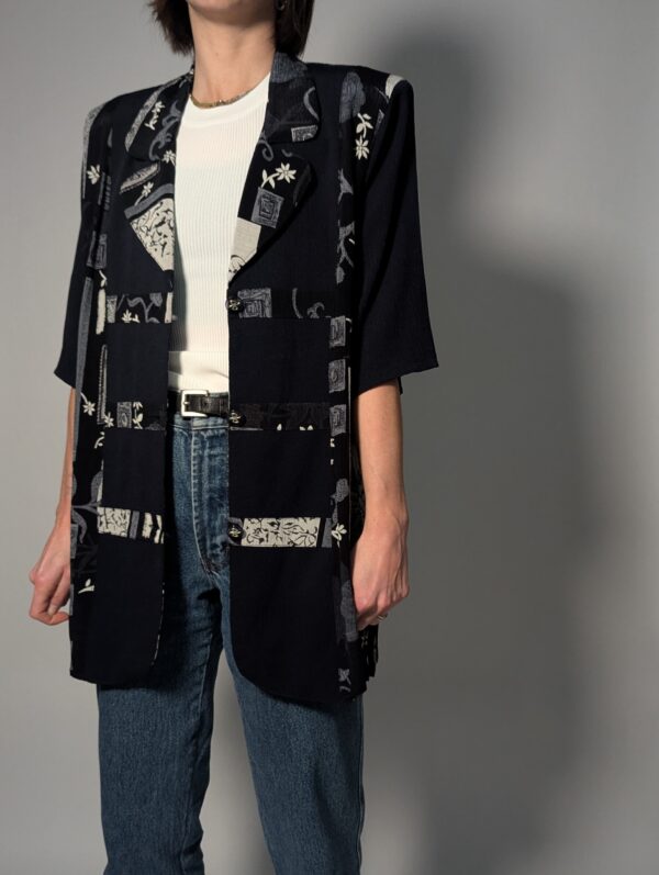 Zwarte vintage lange blouse met korte mouwen en grafisch patchworkpatroon in zwart-wit en grijstinten.