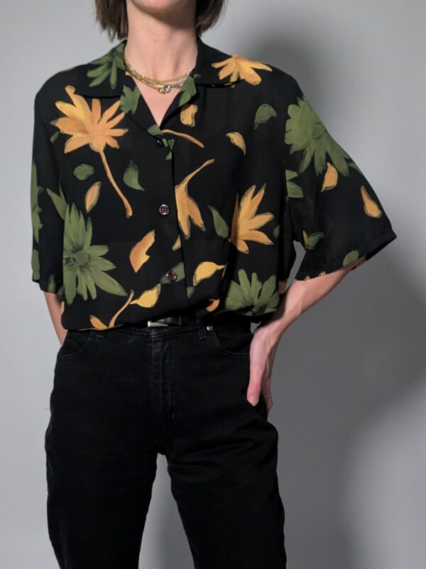 Zwarte vintage blouse met korte mouwen en grote bloemenprint in groen- en geeltinten.