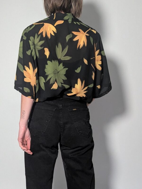 Zwarte vintage blouse met korte mouwen en grote bloemenprint in groen- en geeltinten.