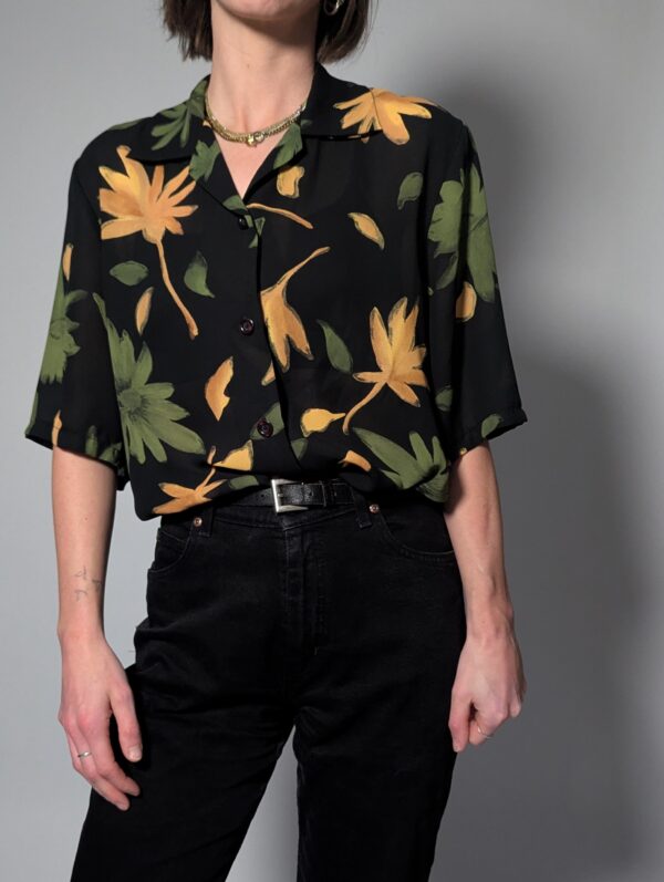 Zwarte vintage blouse met korte mouwen en grote bloemenprint in groen- en geeltinten.