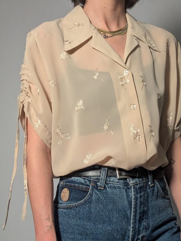 Semi-transparante vintage blouse in zandtint met geborduurde bloemetjes, korte mouwen en luchtige pasvorm.