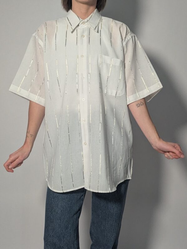 Witte vintage blouse met korte mouwen, oversized fit, borstzak en subtiele glanzende verticale strepen.