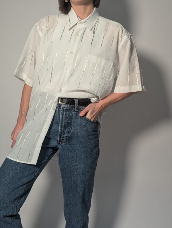 Witte vintage blouse met korte mouwen, oversized fit, borstzak en subtiele glanzende verticale strepen.