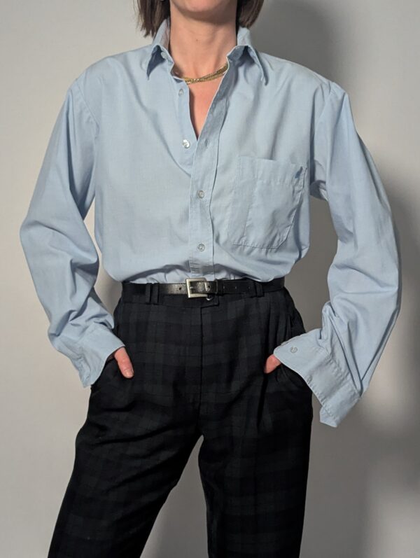 Lichtblauwe vintage blouse met lange mouwen, klassieke kraag, borstzak en rechte relaxte pasvorm.