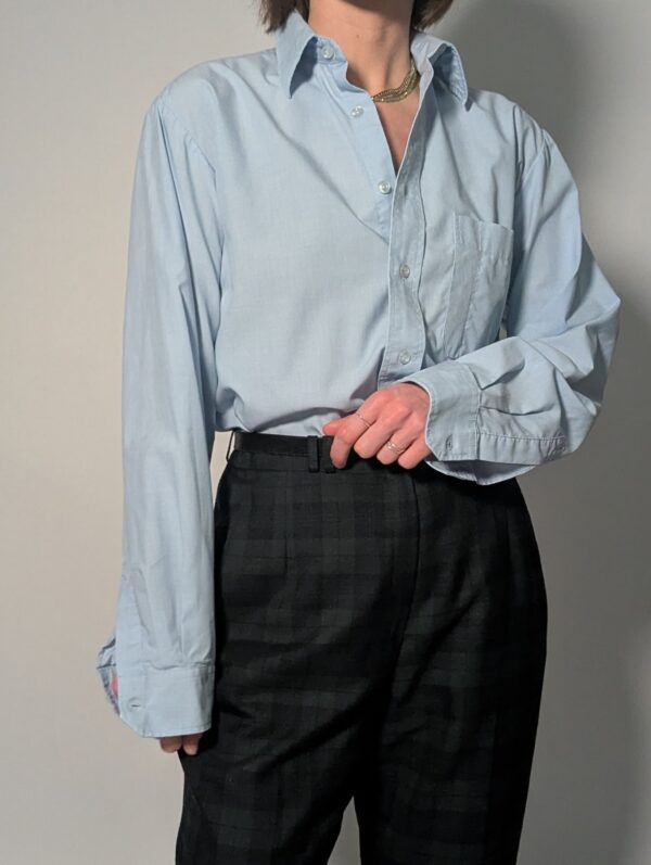 Lichtblauwe vintage blouse met lange mouwen, klassieke kraag, borstzak en rechte relaxte pasvorm.