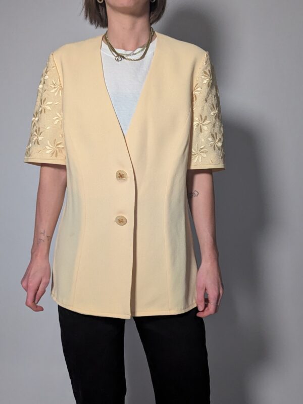 Vintage lichtgele blazer met korte mouwen met bloemenkant, diepe V-hals en lange getailleerde pasvorm.
