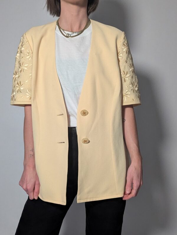 Vintage lichtgele blazer met korte mouwen met bloemenkant, diepe V-hals en lange getailleerde pasvorm.