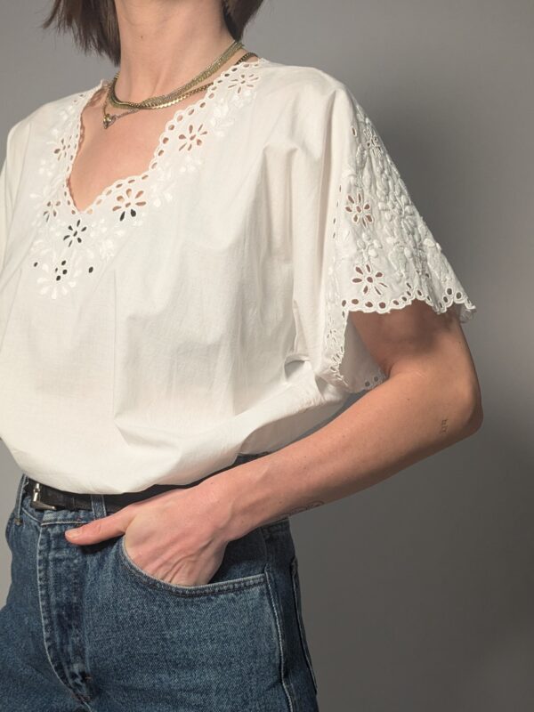 Witte vintage blouse met korte mouwen, broderie details en sierlijke V-hals.