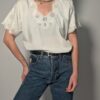 Witte vintage blouse met korte mouwen, broderie details en sierlijke V-hals.