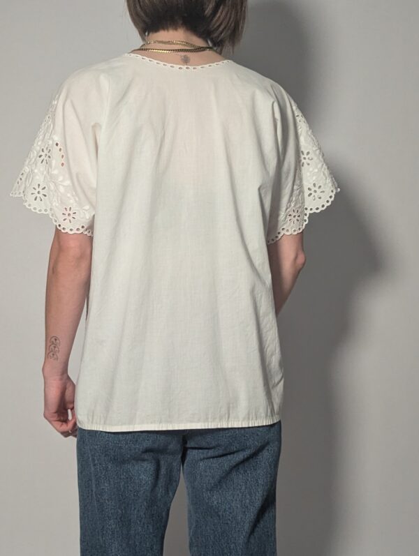 Witte vintage blouse met korte mouwen, broderie details en sierlijke V-hals.