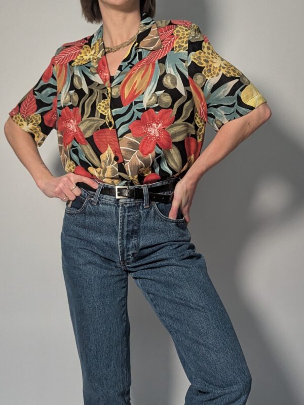 Vintage blouse met korte mouwen, zwarte basis en kleurrijke bloemen- en bladprint in rood, geel, groen en blauw.