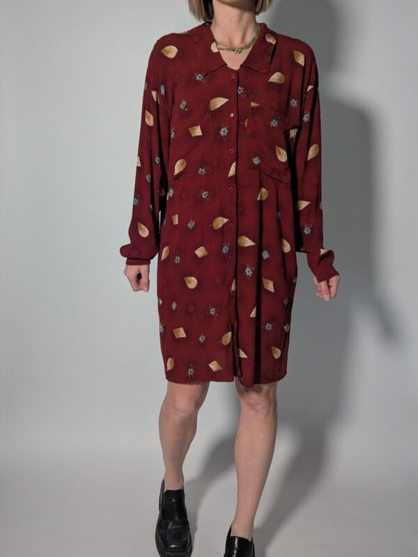 Vintage bordeauxrode jurk met lange mouwen, knoopsluiting en subtiele print van blaadjes en kleine bloemdetails, zonder riem.