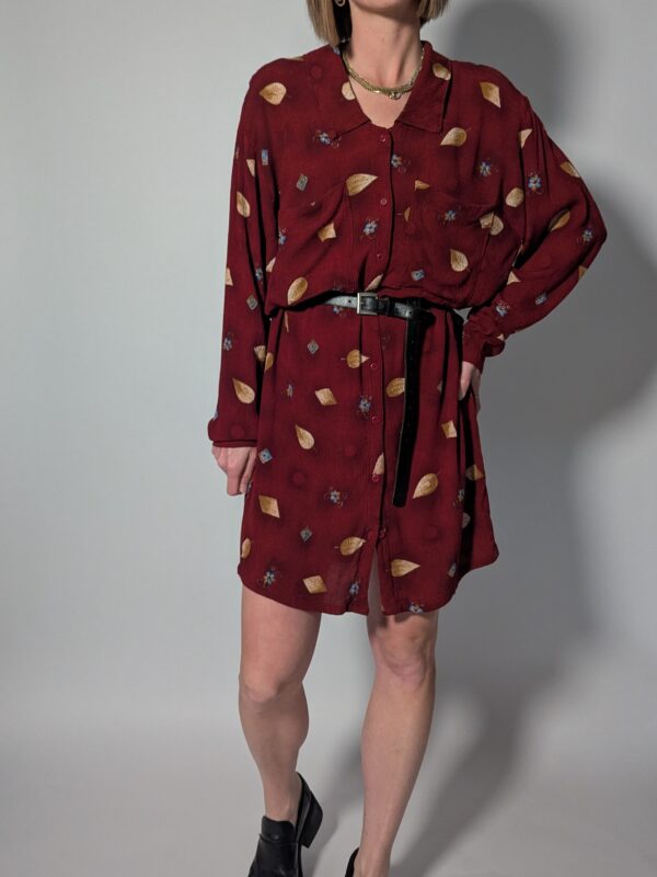 Vintage bordeauxrode jurk met lange mouwen, knoopsluiting en subtiele print van blaadjes en kleine bloemdetails, zonder riem.