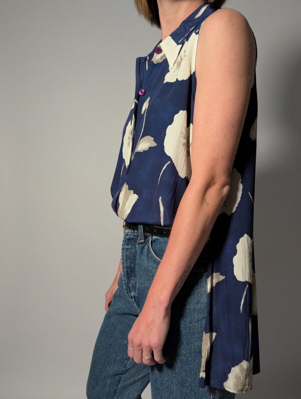 Vintage lange mouwloze blouse in diepblauw met grote bloemenprint in crème en opvallende paarse knopen.