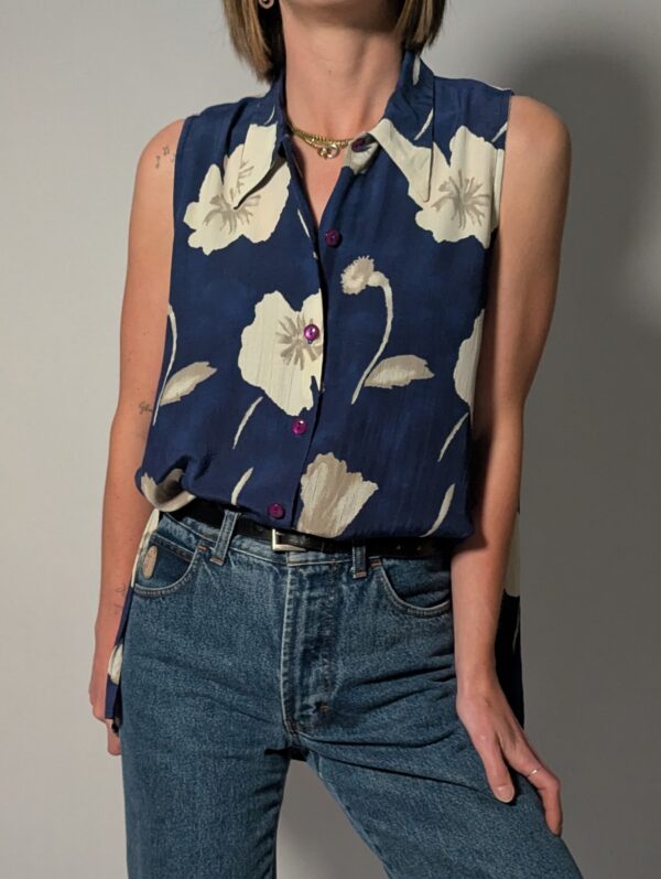Vintage lange mouwloze blouse in diepblauw met grote bloemenprint in crème en opvallende paarse knopen.